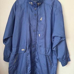 May include: A vintage blue jacket with a high collar and button-up front. The jacket features two front pockets, a light beige lining, and a subtle sheen. The sleeves are long and the jacket has a relaxed fit, perfect for layering.