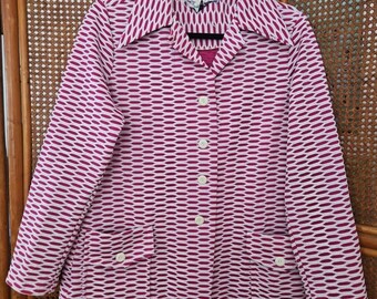 May include: A pink and white patterned long-sleeved button-up jacket with a collar. The jacket has two pockets and white buttons.