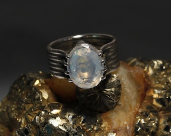 May include: A silver ring with a large, oval-shaped, milky white gemstone set in a textured band.