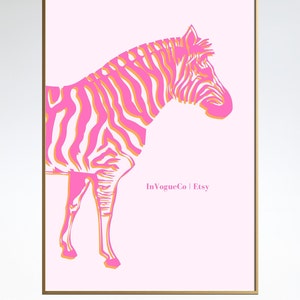 May include: A framed art print featuring a stylized zebra illustration. The zebra is depicted in shades of pink and orange against a light pink background. The artwork is framed in a gold-colored frame. The text "InVogueCo | Etsy" is visible.