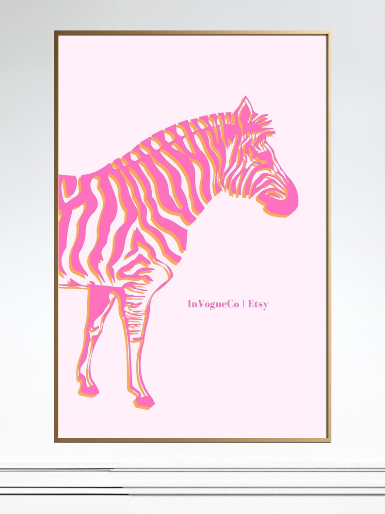 May include: A framed art print featuring a stylized zebra illustration. The zebra is depicted in shades of pink and orange against a light pink background. The artwork is framed in a gold-colored frame. The text "InVogueCo | Etsy" is visible.