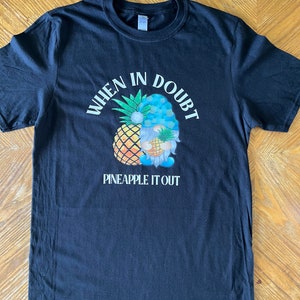 May include: Black t-shirt with a white graphic of a gnome holding a pineapple. The text "When in doubt, pineapple it out" is printed on the shirt.