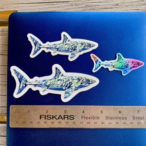Three shark stickers on a laptop with ruler for sizing.