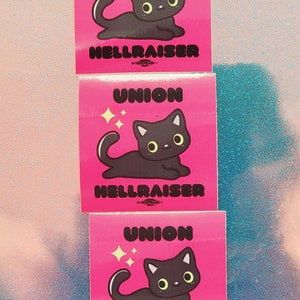 May include: Three pink stickers with black cartoon cats and the text "UNION HELLRAISER" on each.