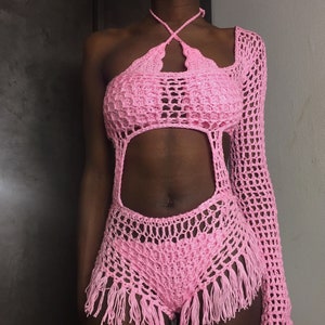 Peut inclure: Combinaison de bain en crochet rose avec un haut halter et une manche longue. La combinaison de bain a un design d&eacute;coup&eacute; et des d&eacute;tails en frange.