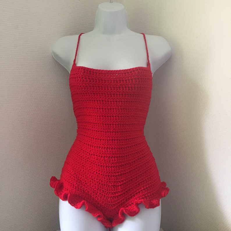 May include: Red crocheted swimsuit with a ruffled bottom.