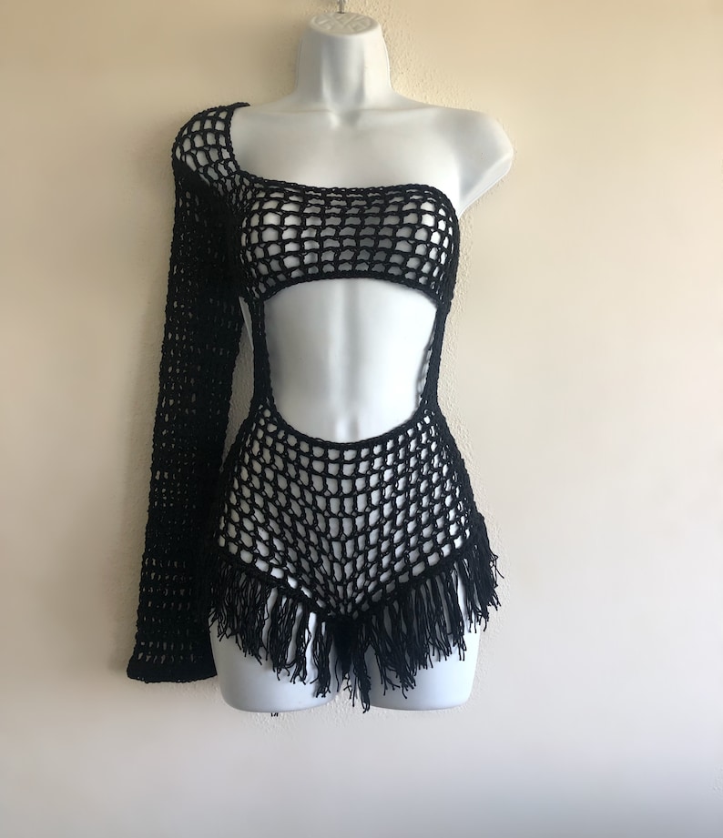 Peut inclure: Combinaison de bain noire en crochet avec une manche longue d'un c&ocirc;t&eacute; et une bordure en franges en bas.