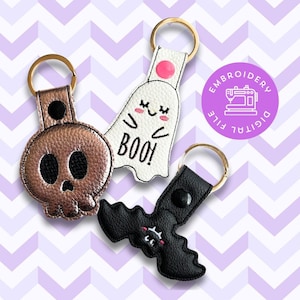 May include: Three Halloween-themed keychains: a black and white ghost with the text "BOO!" a black bat with pink cheeks, and a gold skull with black eyes.