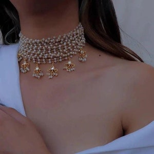 May include: A multi-layered gold choker necklace with pearl and crystal accents. The necklace features a series of delicate chains adorned with small pearls and sparkling crystals, creating a luxurious and elegant look.