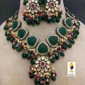 Peut inclure: Un collier et des boucles d'oreilles assortis de couleur verte et dorée avec un motif floral et des accents de pierres précieuses vertes. Le collier a un pendentif avec un motif floral et des pierres précieuses vertes. Les boucles d'oreilles ont un motif floral avec des pierres précieuses vertes.