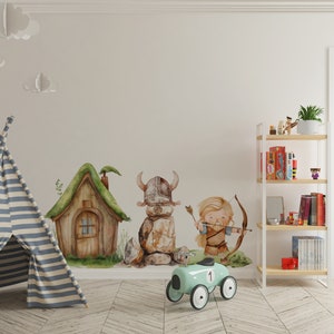 May include: A light blue toy car with a number "1" on the side, a wooden house with a green roof, a stone figure with a horned helmet, and a cartoon character with a bow and arrow. The scene is set against a white wall with a white bookshelf in the background.