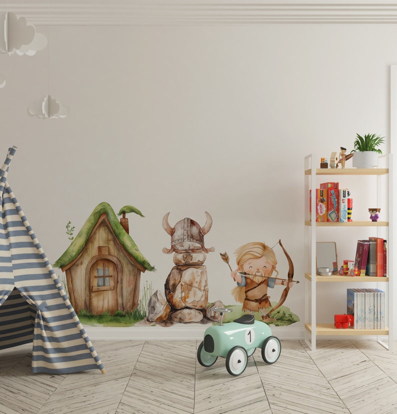 May include: A light blue toy car with a number "1" on the side, a wooden house with a green roof, a stone figure with a horned helmet, and a cartoon character with a bow and arrow. The scene is set against a white wall with a white bookshelf in the background.