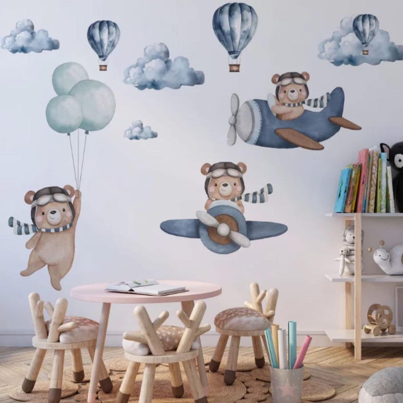 May include: A set of wall decals featuring watercolor illustrations of brown bears wearing aviator goggles and scarves, flying in blue airplanes and holding balloons, accompanied by blue clouds and hot air balloons in various sizes.
