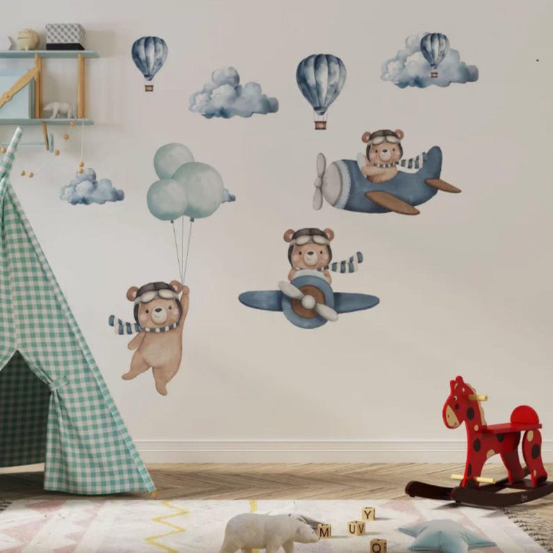 May include: A set of wall decals featuring watercolor-style illustrations of brown bears wearing aviator goggles and scarves, flying in blue airplanes and holding clusters of light blue balloons, accompanied by various blue clouds and hot air balloons.