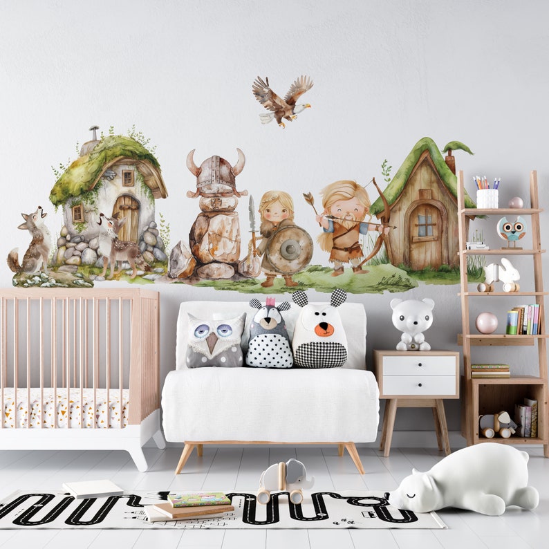 May include: A nursery room with a white crib, a white couch with four pillows, a white bear, a wooden shelf with books and toys, and a wall with a whimsical watercolor mural of a forest scene with houses, animals, and characters.