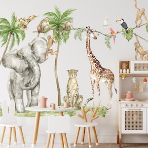 Könnte beinhalten: Ein Wandaufkleber-Set mit Dschungeltieren im Aquarell-Stil, das eine Giraffe, einen Elefanten, einen Geparden, Affen und Papageien zeigt. Die Aufkleber sind auf einer weißen Wand in einem Raum mit einer Spielküche und Holzstühlen zu sehen.