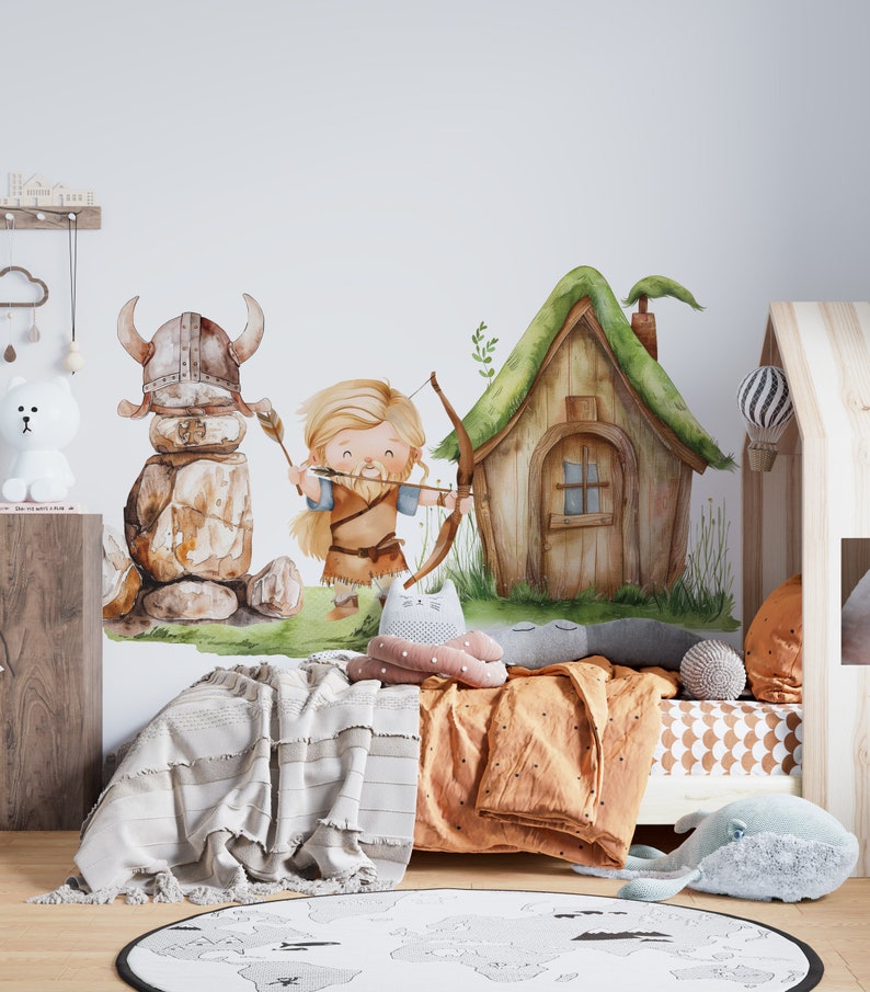 May include: A watercolor illustration of a Viking warrior with a bow and arrow, a stone Viking helmet, and a small wooden house with a green roof. The illustration is on a white wall in a child's bedroom with a bed, pillows, and a rug.