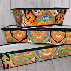 Pu&ograve; includere: Tre vasi da fiori in ceramica colorati con bordi neri e intricati motivi floreali in tonalit&agrave; di arancione, verde, blu e bianco.