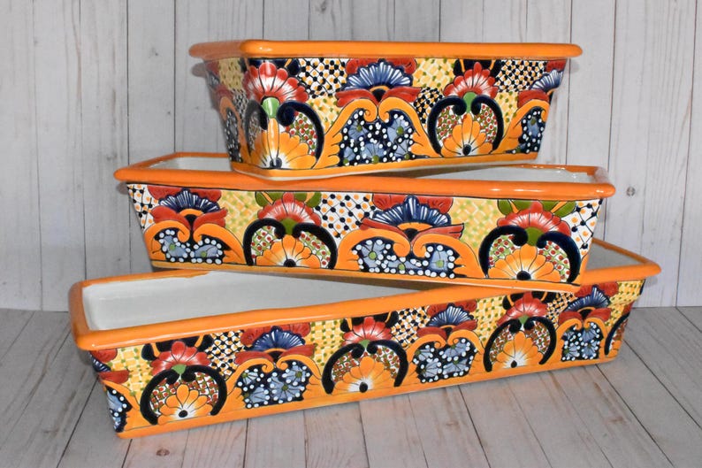 Pu&ograve; includere: Tre vasi in ceramica colorati con bordi arancioni e intricati disegni floreali in tonalit&agrave; di blu, rosso, giallo e verde. I vasi sono impilati uno sopra l'altro.