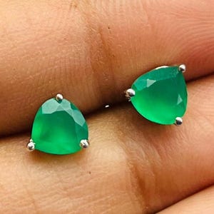 Könnte beinhalten: Ein Paar silberne Ohrstecker mit grünen Edelstein-Akzenten. Die Edelsteine sind dreieckig und facettiert.