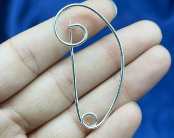 May include: A silver safety pin with a unique, curved design. The pin is open and ready to be used.
