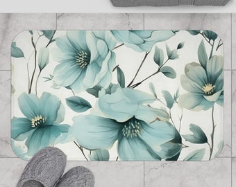 Könnte beinhalten: Eine weiße Badematte mit einem blauen Blumenmuster. Die Blumen sind groß und haben einen Aquarell-Effekt. Die Matte ist rechteckig und hat eine rutschfeste Rückseite.