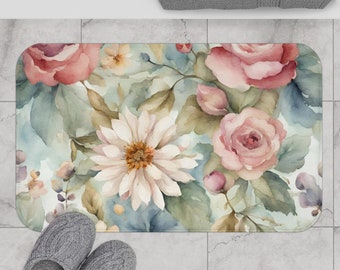 Può includere: Un tappetino da bagno floreale ad acquerello con fiori rosa e bianchi su uno sfondo blu chiaro.