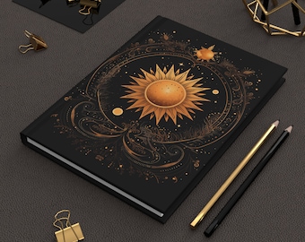 May include: A black notebook featuring a gold sun and floral design. The sun has a gold centre and rays. The design is intricate and detailed.