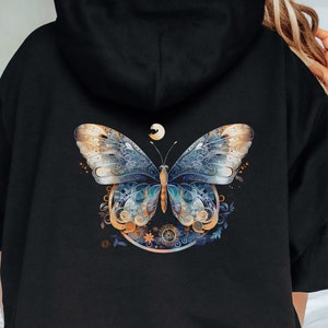 Pode incluir: Moletom preto com um design detalhado de borboleta nas costas. A borboleta tem asas azuis, douradas e brancas com padr&otilde;es intrincados. Uma pequena lua est&aacute; acima da borboleta, dentro de uma moldura circular.
