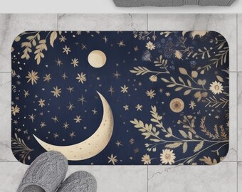 May include: A navy blue bath mat featuring a crescent moon and a full moon design. The moons are gold and surrounded by gold stars and floral accents.