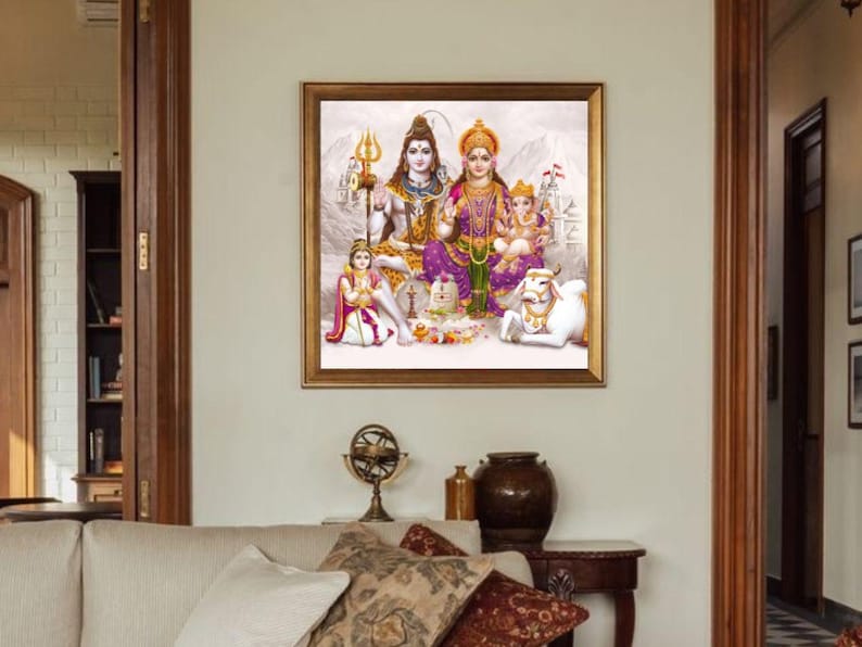 May include: A framed painting depicting a Hindu deity family. The painting features Shiva, Parvati, Ganesha, and a white cow. The painting is set against a white background with a mountain range in the distance.