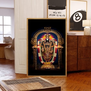 May include: A framed print of a Hindu deity, adorned with intricate gold jewelry and colorful garlands. The deity stands in front of an ornate golden archway, with lit candles on either side. The background is a deep black, enhancing the vibrant colors.