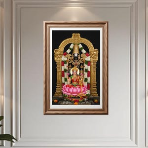 Puede incluir: Una obra de arte enmarcada que presenta una vibrante representación de deidades hindúes. La figura central, sentada sobre una flor de loto, está adornada con coloridas prendas y joyas. El fondo es negro intenso y el marco es marrón cálido.