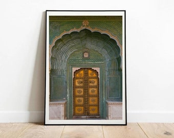 May include: A large, ornate, golden door with intricate carvings is framed by a green archway with detailed tile work. The door is set within a larger building with a white marble base.