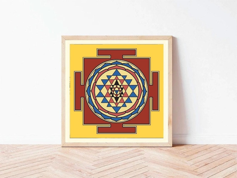 May include: A framed print of a colorful geometric design, known as a Sri Yantra, with a yellow background, red and blue accents, and a central star.