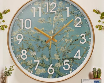 May include: A round, gold-framed wall clock with a white face and black numbers. The clock face features a painting of a blue sky with a white flowering tree. The clock hands are gold.