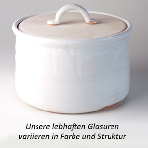 Puede incluir: Tarro de almacenamiento de cerámica blanca con tapa de madera y asa. El tarro tiene un esmalte moteado y una superficie ligeramente texturizada.