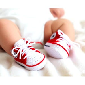 Baby trägt weiß-rote gehäkelte Sneaker – Produkt in Aktion