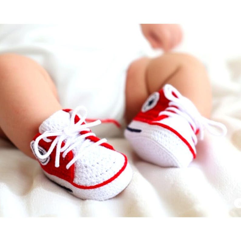 Baby trägt weiß-rote gehäkelte Sneaker – Produkt in Aktion