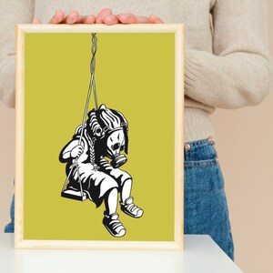 May include: Black and white artwork of a child wearing a gas mask, swinging on a swing. The artwork is framed in a light wood frame and set against a yellow-green background. The image is a print.