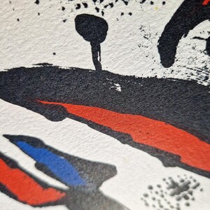 May include: Abstract art print with a textured white background. Bold black brushstrokes and splatters are accented by red and blue shapes. The artwork features a unique, expressive style.
