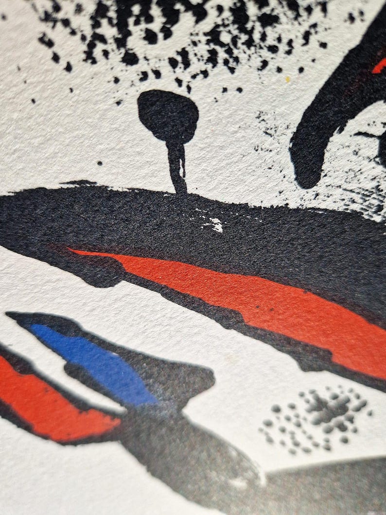 May include: Abstract art print with a textured white background. Bold black brushstrokes and splatters are accented by red and blue shapes. The artwork features a unique, expressive style.