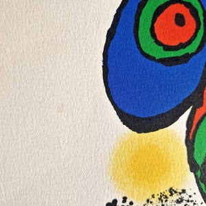 May include: Abstract art print featuring bold shapes and colors. The artwork showcases a blue, red, and green design with black outlines and a yellow circle on a white background. The print has a textured paper appearance.