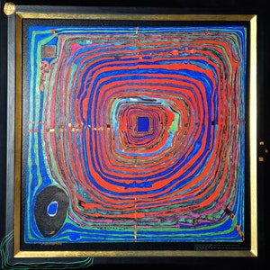 May include: Abstract art print featuring concentric, swirling patterns in red, blue, green, and purple. The artwork is framed in black with a gold inner border. A black oval shape with a blue center is in the lower left corner.