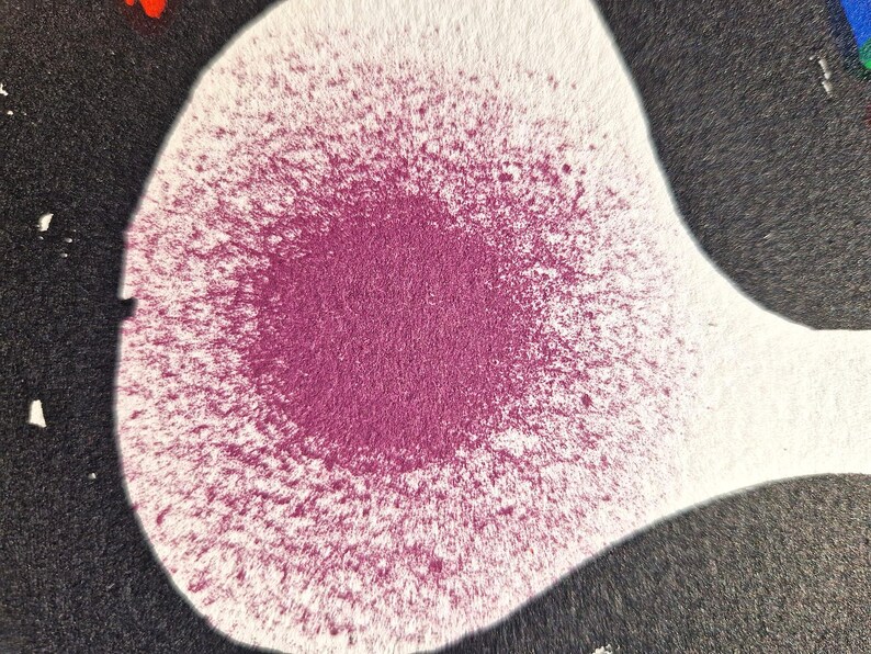 May include: Abstract artwork featuring a white, teardrop-shaped form with a central burst of magenta spray paint. The magenta color fades outwards, contrasting with the white background and a surrounding black area. The image has a textured appearance.