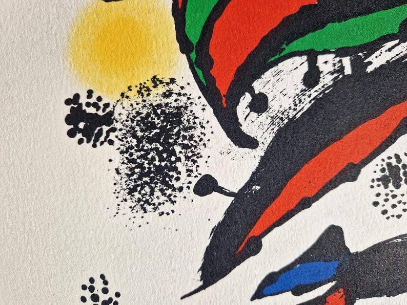 May include: Abstract art print with a white background and bold, colorful shapes. Features a yellow circle, black splatters, and red, green, and blue brushstrokes. The artwork has a textured appearance.