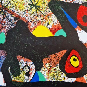 May include: Abstract art print with a black, white, red, yellow, and green color scheme. The print features a large black shape with a yellow sun and a red and yellow eye.