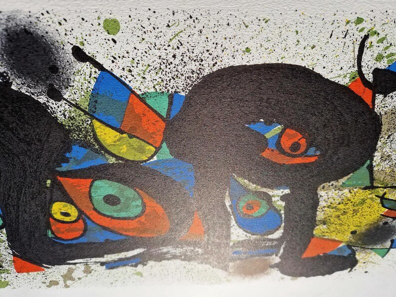 May include: Abstract art print featuring bold black shapes with orange, yellow, blue, and green accents. The artwork includes splatters and geometric forms, creating a dynamic composition. The print is on a white background.