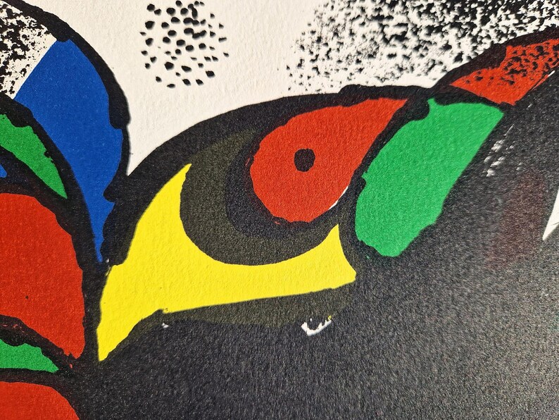 May include: Abstract art print featuring bold colors and shapes. The artwork showcases a black background with a vibrant eye-like design in red, green, yellow, and blue. The composition includes a white background with black dots.