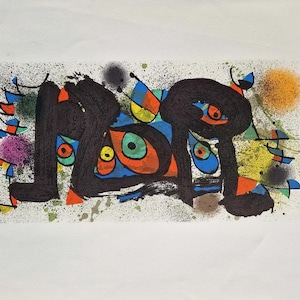 May include: Abstract art print with black, orange, blue, and green shapes on a white background. The artwork features splattered paint and colorful, stylized figures, creating a vibrant and dynamic composition.